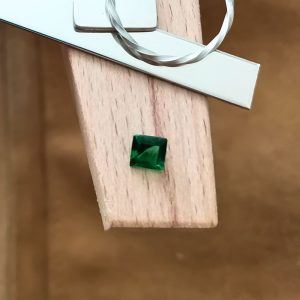 The green tsavorite garnet square displayed on a jewellers bench peg with some sterling silver sheet and wire.
