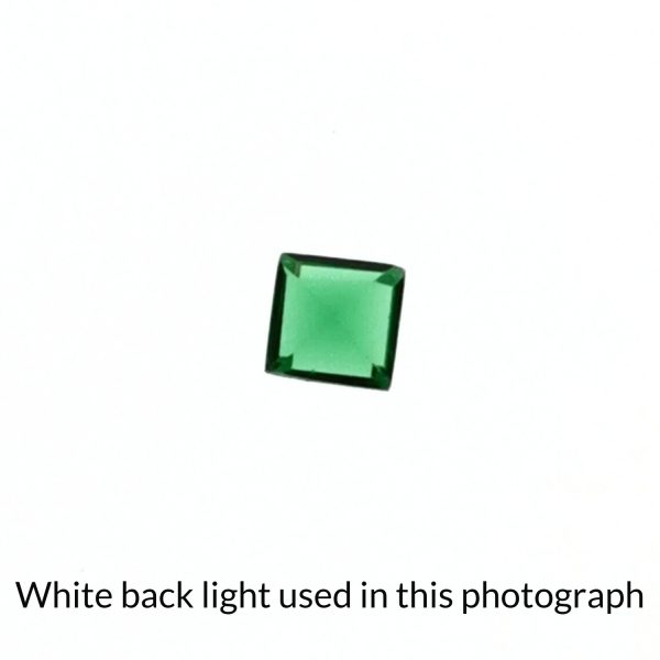 The square green garnet gem is being back-lit with a bright white light to show any inclusions within the gem more clearly.