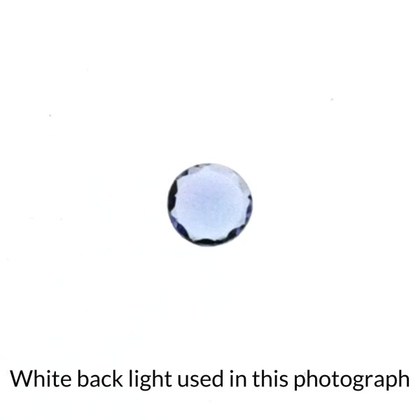 The round tanzanite gem is being back-lit with a bright white light to show any inclusions within the gem more clearly.
