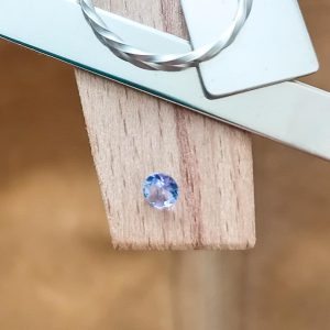 The blue tanzanite round displayed on a jewellers bench peg with some sterling silver sheet and wire.