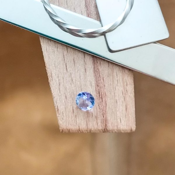 The blue tanzanite round displayed on a jewellers bench peg with some sterling silver sheet and wire.