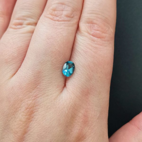 The blue topaz gemstone resting on a hand to give an idea of the gemstones size and colour.