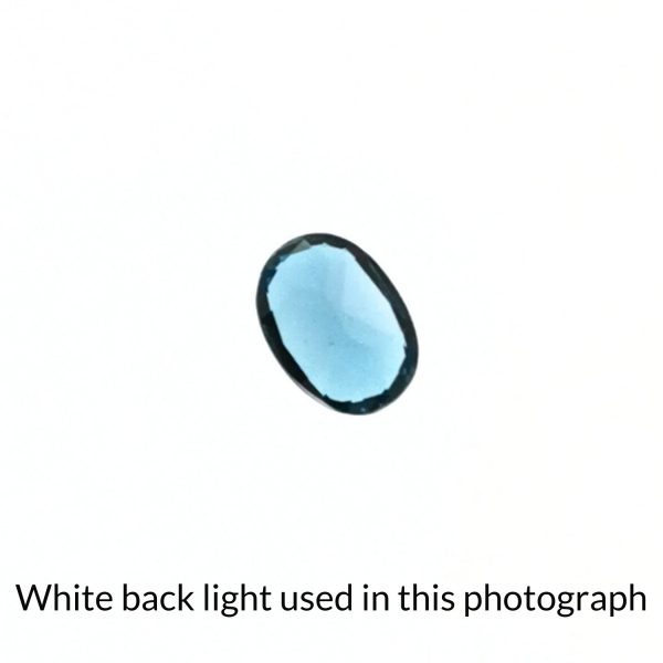 The oval topaz gem is being back-lit with a bright white light to show any inclusions within the gem more clearly.