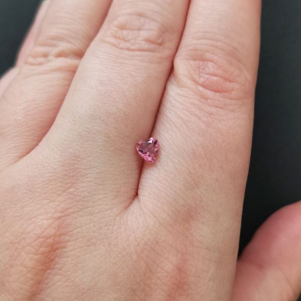 The pink tourmaline gemstone resting on a hand to give an idea of the gemstones size and colour.