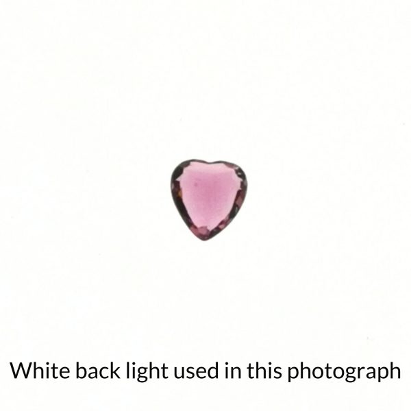 The heart shaped tourmaline gem is being back-lit with a bright white light to show any inclusions within the gem more clearly.