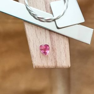 The pink tourmaline heart displayed on a jewellers bench peg with some sterling silver sheet and wire.