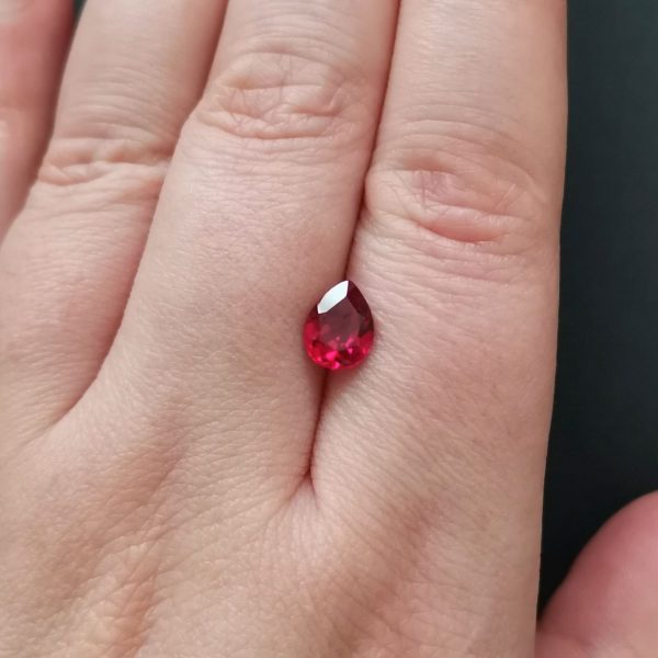 The red lab grown ruby gemstone resting on a hand to give an idea of the gemstones size and colour.