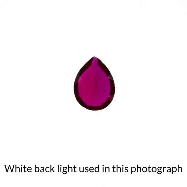 The teardrop shaped lab grown ruby gem is being back-lit with a bright white light to show any inclusions within the gem more clearly.