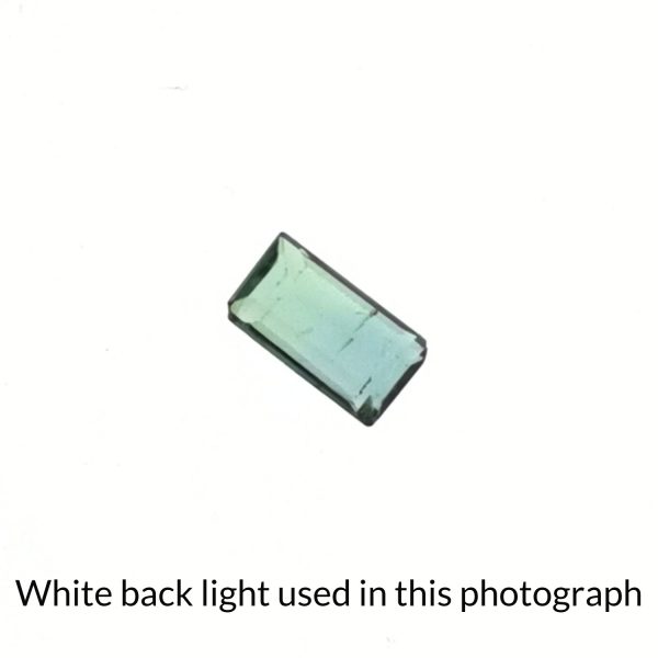 The rectangular shaped tourmaline gem is being back-lit with a bright white light to show any inclusions within the gem more clearly.