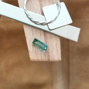 The two tone tourmaline rectangle displayed on a jewellers bench peg with some sterling silver sheet and wire.