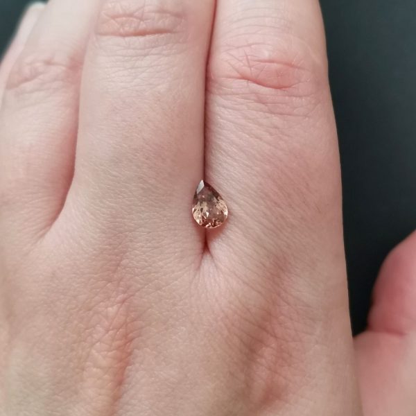 The brown garnet gemstone resting on a hand to give an idea of the gemstones size and colour.