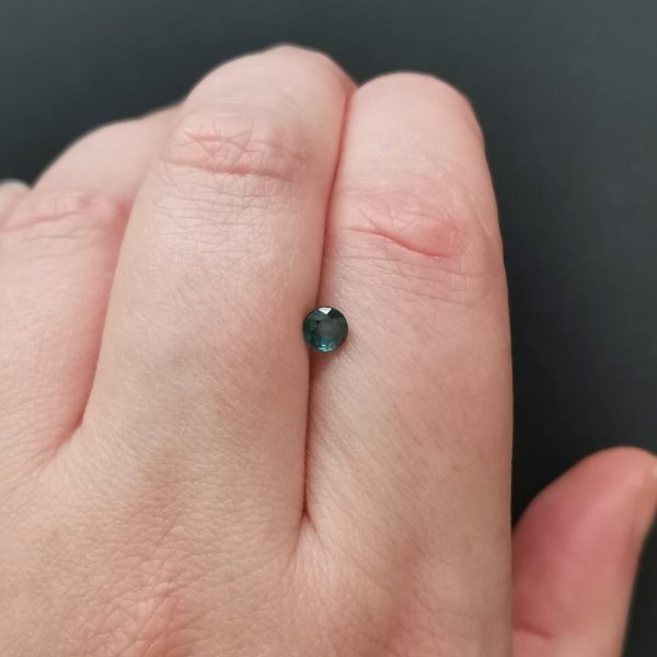 The green sapphire gemstone resting on a hand to give an idea of the gemstones size and colour.