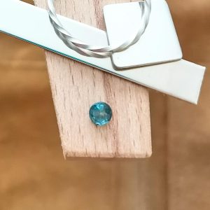 The two tone blue and yellow sapphire round displayed on a jewellers bench peg with some sterling silver sheet and wire.