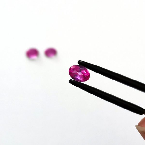 A photo of the crown area of the bright pink colour coated topaz against a white background