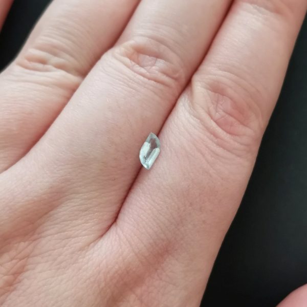 The pale blue aquamarine gemstone resting on a hand to give an idea of the gemstones size and colour.