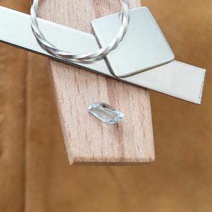 The fancy blue aquamarine displayed on a jewellers bench peg with some sterling silver sheet and wire.