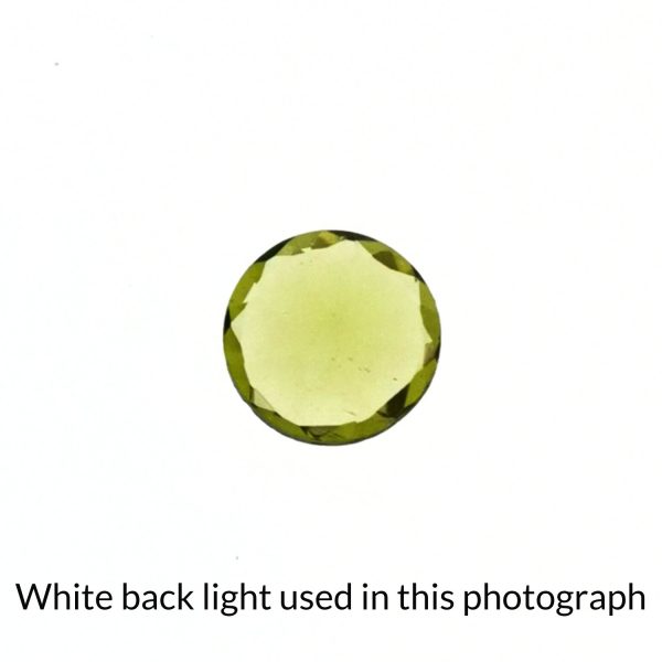 The round shaped peridot gem is being back-lit with a bright white light to show any inclusions within the gem more clearly.