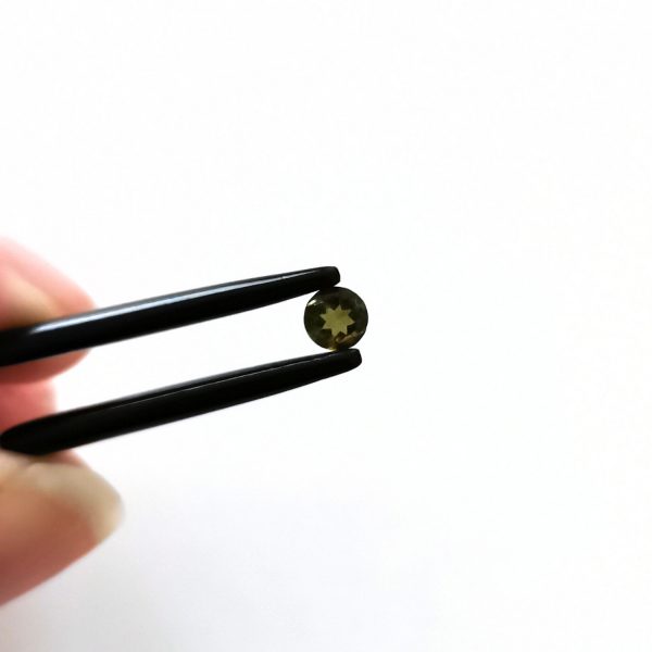A photo of the crown area of the dark green tourmaline against a white background