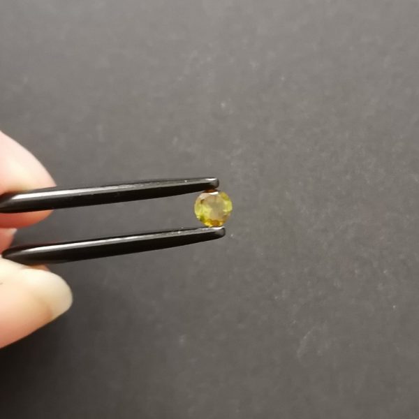 A photo of the crown area of the dark olive green tourmaline against a black background