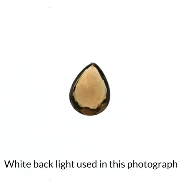 The tearsrop shaped sapphire gem is being back-lit with a bright white light to show any inclusions within the gem more clearly.