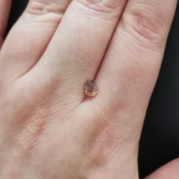 The brown sapphire gemstone resting on a hand to give an idea of the gemstones size and colour.