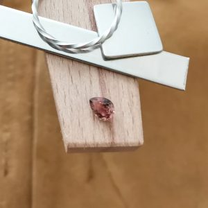 The brown teardrop sapphire displayed on a jewellers bench peg with some sterling silver sheet and wire.
