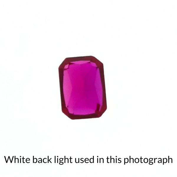 The lab grown ruby gem is being back-lit with a bright white light to show any inclusions within the gem more clearly.