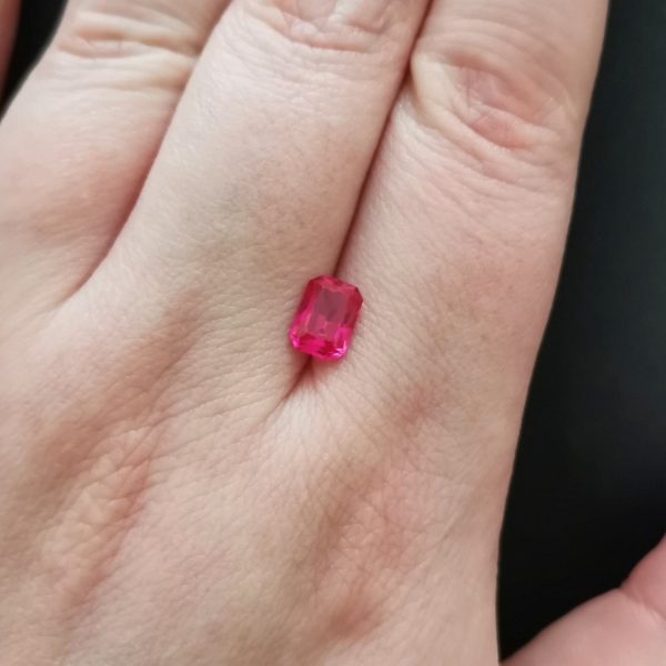 The lab grown ruby gemstone resting on a hand to give an idea of the gemstones size and colour.