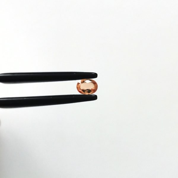 A photo of the crown area of the orange sapphire against a white background