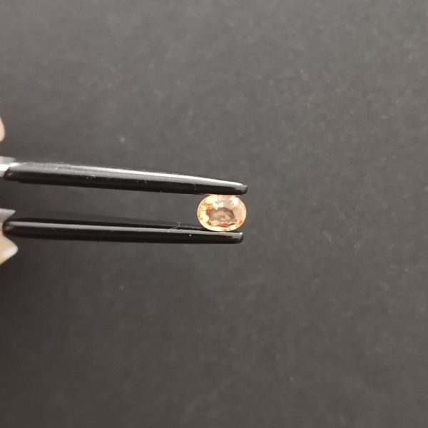 A photo of the crown area of the orange sapphire against a black background
