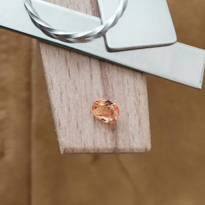 The orange sapphire oval displayed on a jewellers bench peg with some sterling silver sheet and wire.
