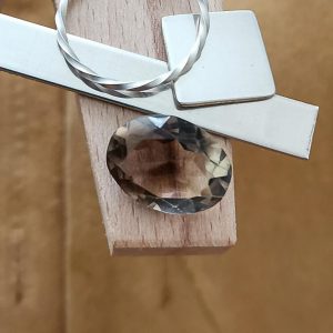 The brown smoky quartz oval displayed on a jewellers bench peg with some sterling silver sheet and wire.