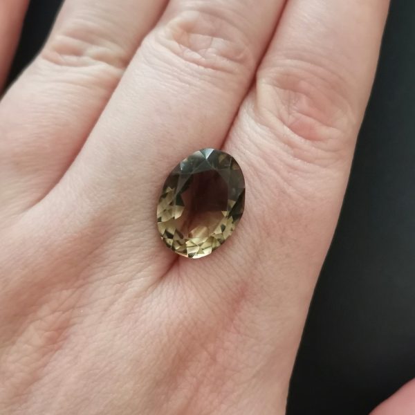 The smoky quartz gemstone resting on a hand to give an idea of the gemstones size and colour.