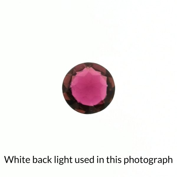 The round shaped tourmaline gem is being back-lit with a bright white light to show any inclusions within the gem more clearly.