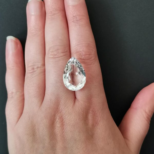 The clear quartz gemstone resting on a hand to give an idea of the gemstones size and colour.