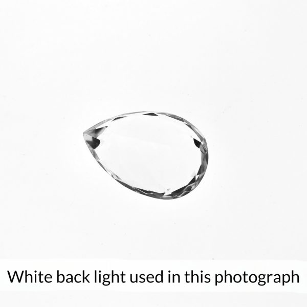 The teardrop shaped clear quartz gem is being back-lit with a bright white light to show any inclusions within the gem more clearly.