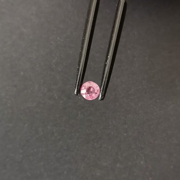 A photo of the crown area of the pinkish red ruby against a black background