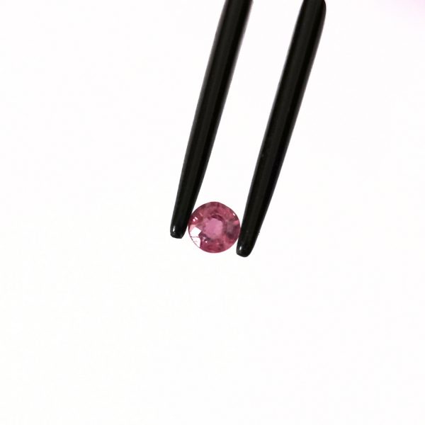 A photo of the crown area of the pinkish red ruby against a white background
