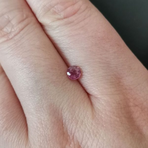 The small ruby gemstone resting on a hand to give an idea of the gemstones size and colour.