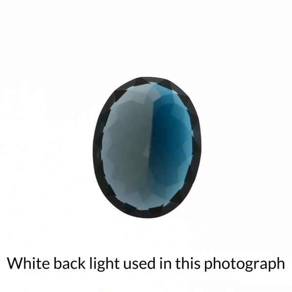 The oval shaped topaz gem is being back-lit with a bright white light to show any inclusions within the gem more clearly.