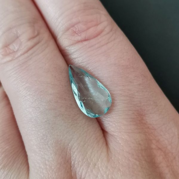 The blue aquamarine gemstone resting on a hand to give an idea of the gemstones size and colour.