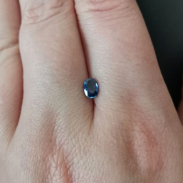 The blue sapphire gemstone resting on a hand to give an idea of the gemstones size and colour.