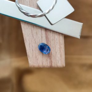 The blue sapphire oval displayed on a jewellers bench peg with some sterling silver sheet and wire.