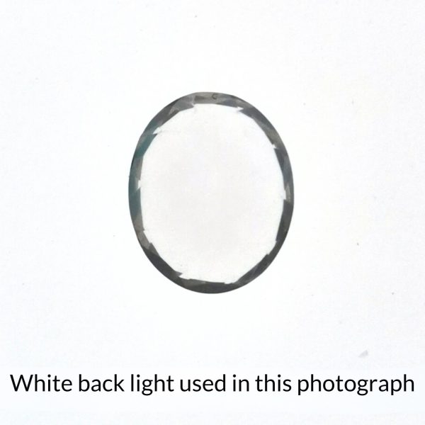 The oval shaped rose quartz gem is being back-lit with a bright white light to show any inclusions within the gem more clearly.