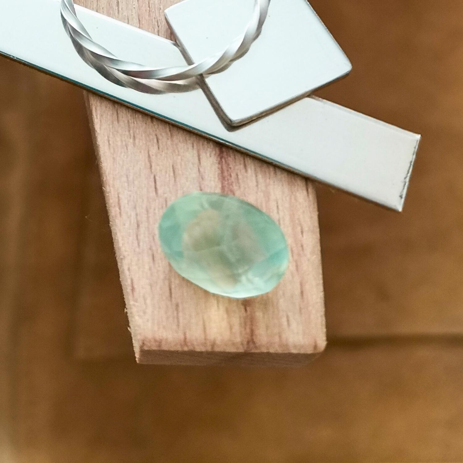The green prehnite oval displayed on a jewellers bench peg with some sterling silver sheet and wire.
