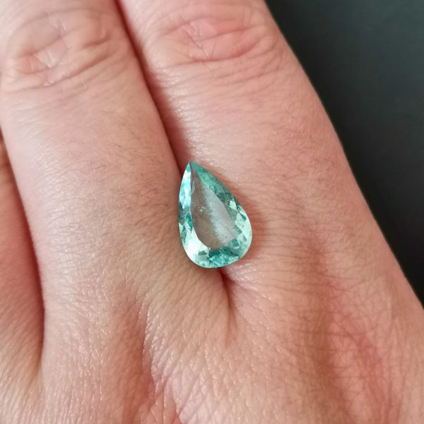 The blue aquamarine gemstone resting on a hand to give an idea of the gemstones size and colour.