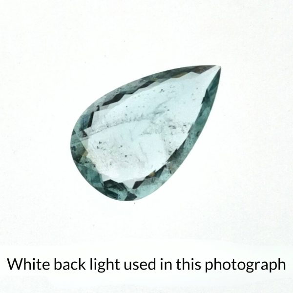 The teardrop shaped aquamarine gem is being back-lit with a bright white light to show any inclusions within the gem more clearly.