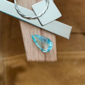 The blue aquamarine teardrop displayed on a jewellers bench peg with some sterling silver sheet and wire.