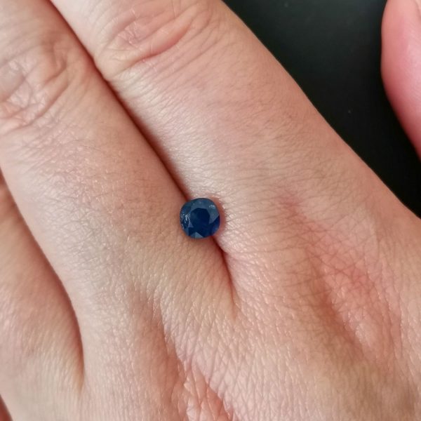 The blue sapphire gemstone resting on a hand to give an idea of the gemstones size and colour.