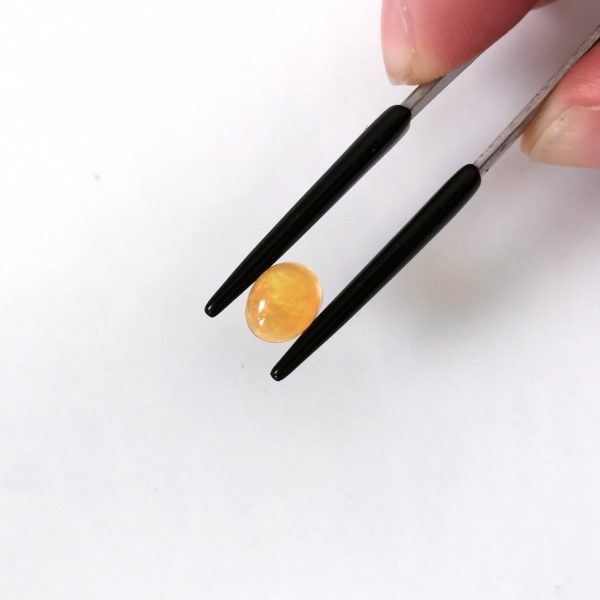 A photo of the crown area of the orange fire opal against a white background